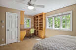 This charming bedroom features a built-in wooden desk and shelving unit, perfect for a home office or study space.