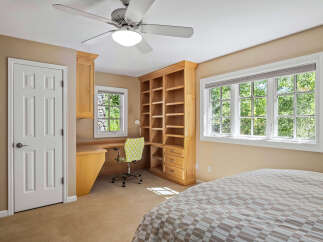 This charming bedroom features a built-in wooden desk and shelving unit, perfect for a home office or study space.