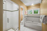 This charming bathroom features a spacious glass-enclosed shower with white tiled walls and a decorative green accent stripe.