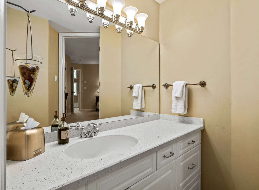 This bathroom features a white vanity with a speckled countertop and a modern sink.