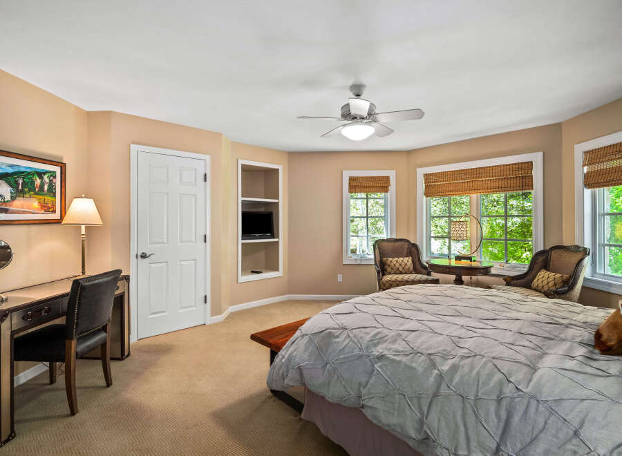 This charming bedroom features a cozy ambiance with its warm, neutral-toned walls and plush carpeting.