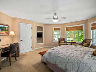 This charming bedroom features a cozy ambiance with its warm, neutral-toned walls and plush carpeting.