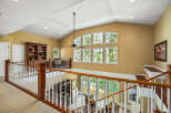 This stunning home features a grand entryway with a vaulted ceiling and a beautiful wooden banister overlooking the living area.