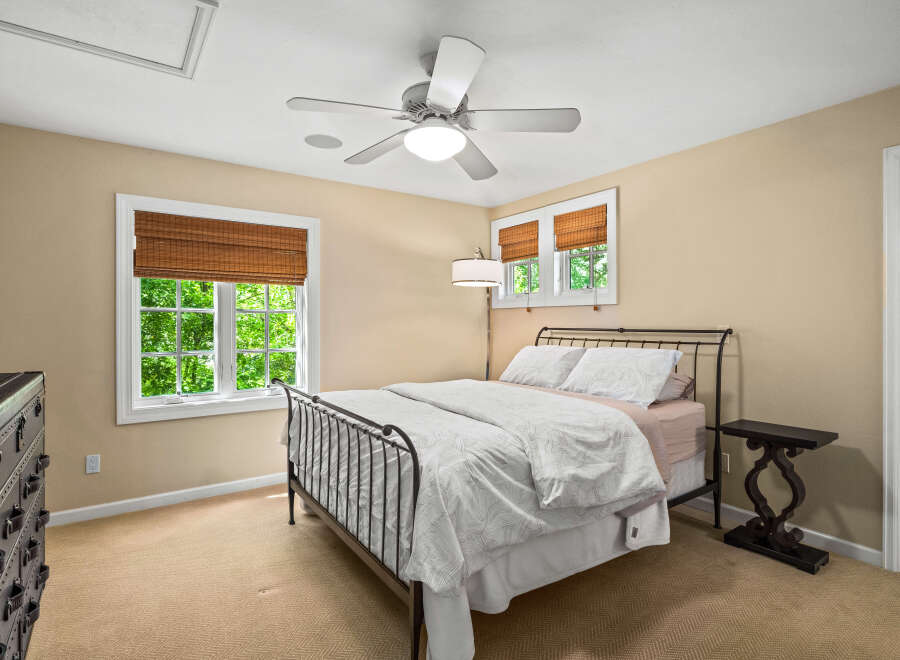 This charming bedroom features a comfortable queen-size bed with a decorative metal frame, complemented by a white duvet and patterned pillows.