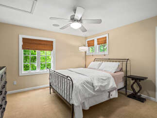 This charming bedroom features a comfortable queen-size bed with a decorative metal frame, complemented by a white duvet and patterned pillows.