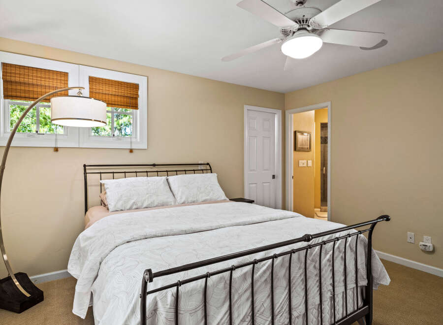 Discover comfort and style in this inviting bedroom, featuring a sleek metal-frame bed adorned with crisp white linens and decorative pillows.