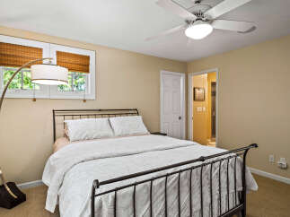 Discover comfort and style in this inviting bedroom, featuring a sleek metal-frame bed adorned with crisp white linens and decorative pillows.