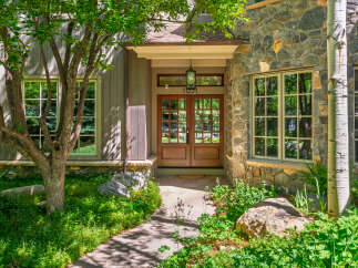Experience the charm of this mountain home featuring a welcoming entrance with double wooden doors and a classic lantern.
