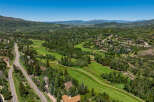 Experience luxury mountain living with this stunning aerial view of a sprawling estate nestled amidst a picturesque golf course and lush green hills.