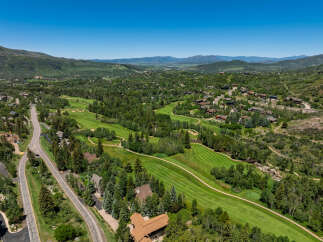 Experience luxury mountain living with this stunning aerial view of a sprawling estate nestled amidst a picturesque golf course and lush green hills.
