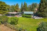 Nestled amidst lush greenery and mature trees, this property offers a serene retreat with ample outdoor living space.