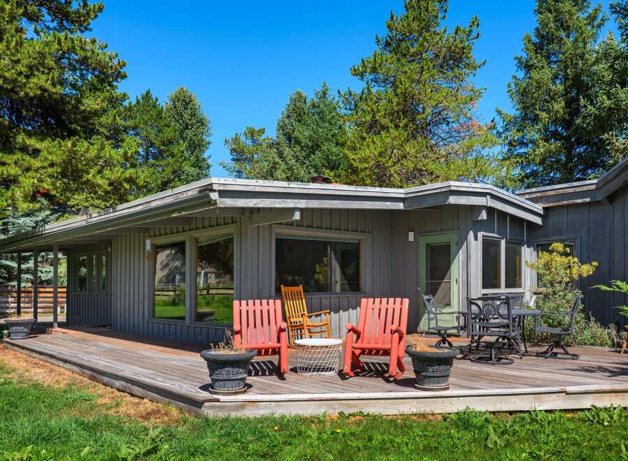 Enjoy outdoor living on this expansive wooden deck, perfect for entertaining or relaxing amidst mature trees.