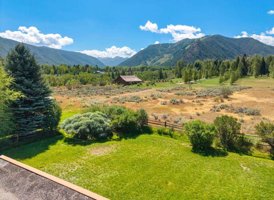 Experience breathtaking mountain views from this stunning property, featuring a picturesque barn and lush green lawns perfect for outdoor enjoyment.