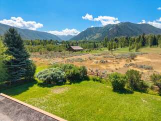 Experience breathtaking mountain views from this stunning property, featuring a picturesque barn and lush green lawns perfect for outdoor enjoyment.