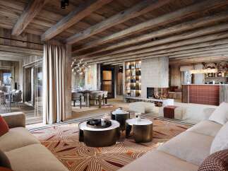 Experience luxury mountain living in this stunning chalet, featuring a grand living area with a modern fireplace and a fully equipped bar.