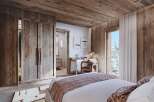 Experience rustic luxury in this charming bedroom, featuring warm wood paneling throughout and a cozy, inviting atmosphere.