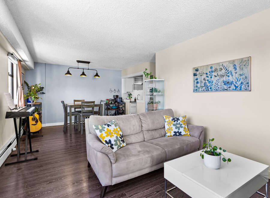 Discover a bright and airy living space featuring a comfortable grey sofa adorned with floral accent pillows, complemented by a modern white coffee table.