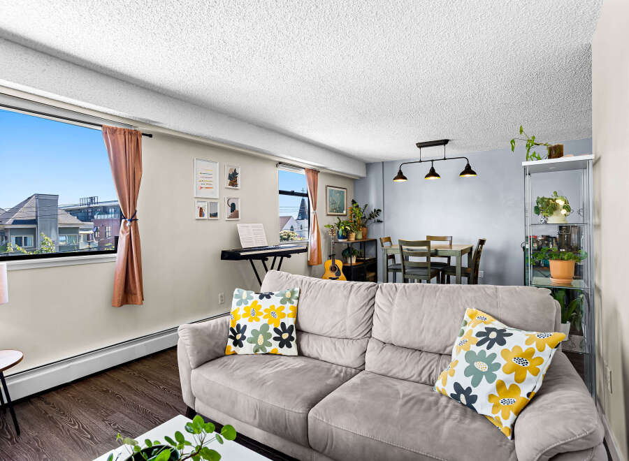 Bright and airy living space featuring a comfortable sofa with decorative pillows and a large window offering scenic views.