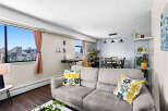 Bright and airy living space featuring a comfortable sofa with decorative pillows and a large window offering scenic views.