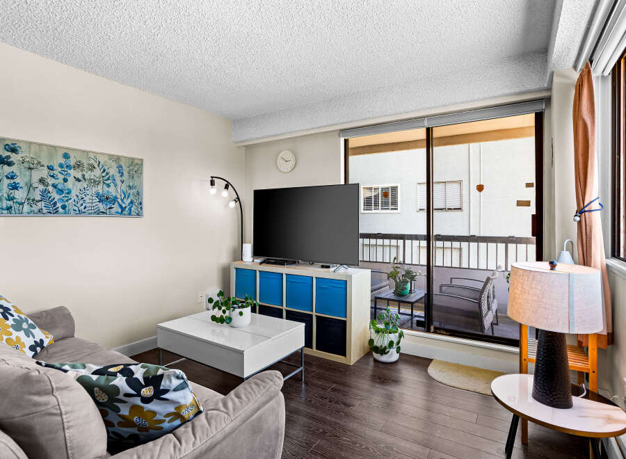 Bright and airy living room featuring a comfortable sofa with decorative pillows, a modern white coffee table, and a large flat-screen TV.