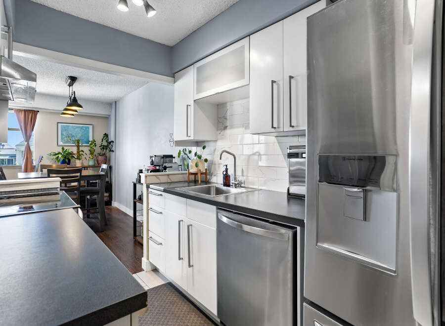 Discover this modern kitchen featuring sleek white cabinetry, a stylish subway tile backsplash, and a durable dark countertop.