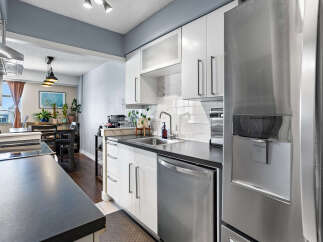 Discover this modern kitchen featuring sleek white cabinetry, a stylish subway tile backsplash, and a durable dark countertop.