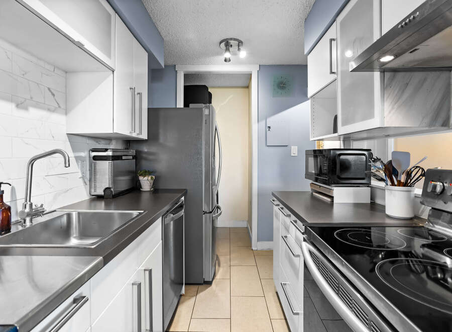 Discover this modern kitchen featuring sleek white cabinetry and a stylish marble backsplash.