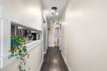 This hallway features a pass-through window with a plant and kitchen appliances visible.