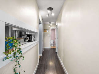 This hallway features a pass-through window with a plant and kitchen appliances visible.