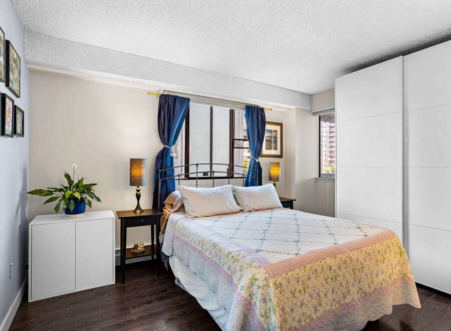 Discover this charming bedroom featuring a comfortable queen-size bed adorned with a floral quilt and crisp white linens.