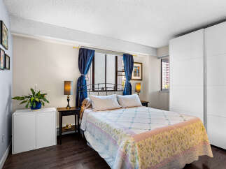 Discover this charming bedroom featuring a comfortable queen-size bed adorned with a floral quilt and crisp white linens.