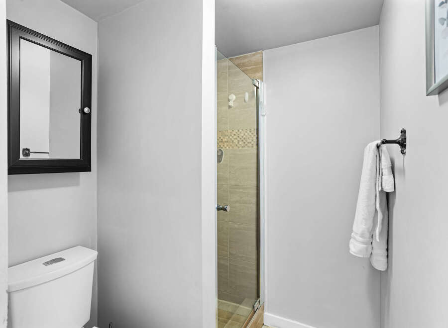 This modern bathroom features a sleek toilet and a stylish medicine cabinet with a black frame.