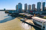 Experience waterfront living at its finest with this stunning aerial view of modern high-rise apartments overlooking the bustling harbor.