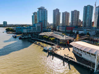 Experience waterfront living at its finest with this stunning aerial view of modern high-rise apartments overlooking the bustling harbor.