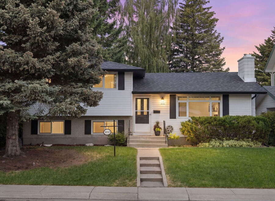 Charming two-story home with a welcoming facade, featuring a well-maintained lawn and mature trees.