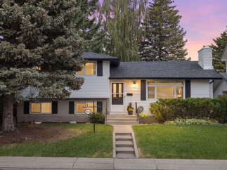 Charming two-story home with a welcoming facade, featuring a well-maintained lawn and mature trees.