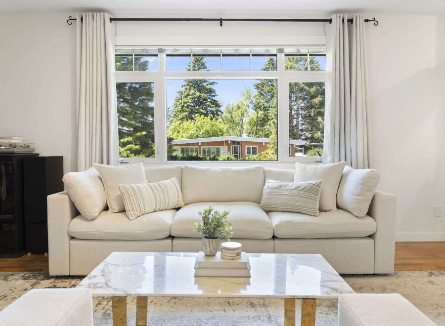 Experience seamless indoor-outdoor living with this spacious living room, featuring a large picture window that floods the space with natural light and offers picturesque views of the surrounding greenery.