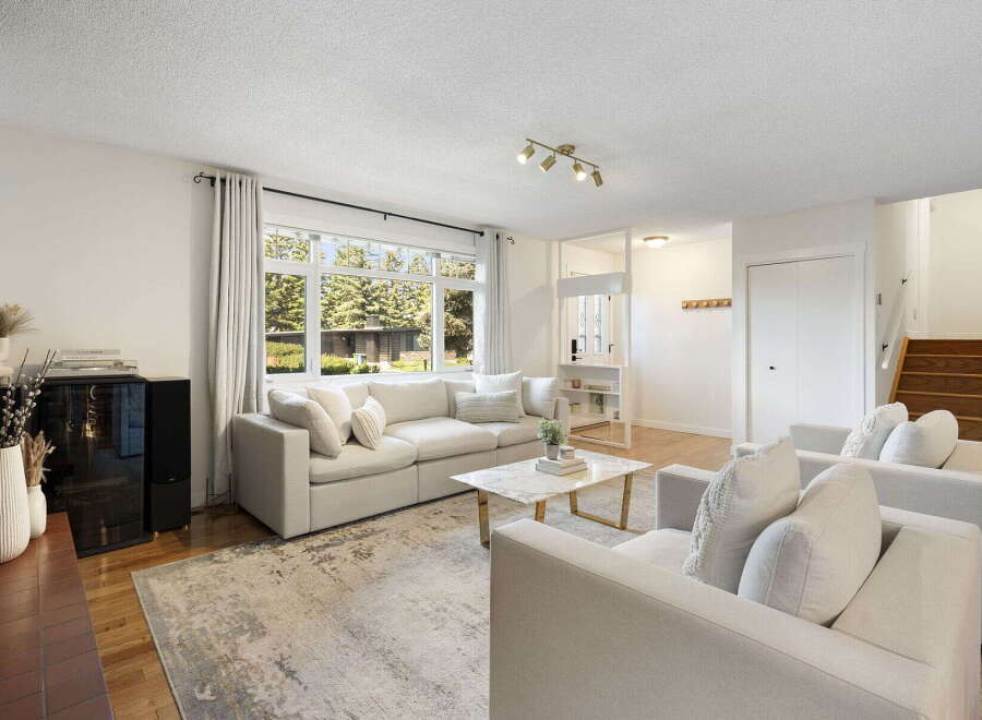 Step into this inviting living room, bathed in natural light from a large picture window overlooking lush greenery.