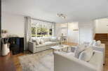 Step into this inviting living room, bathed in natural light from a large picture window overlooking lush greenery.