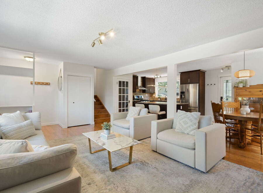 Step into this bright and airy living space, featuring a comfortable sectional sofa and two accent chairs perfect for gathering.