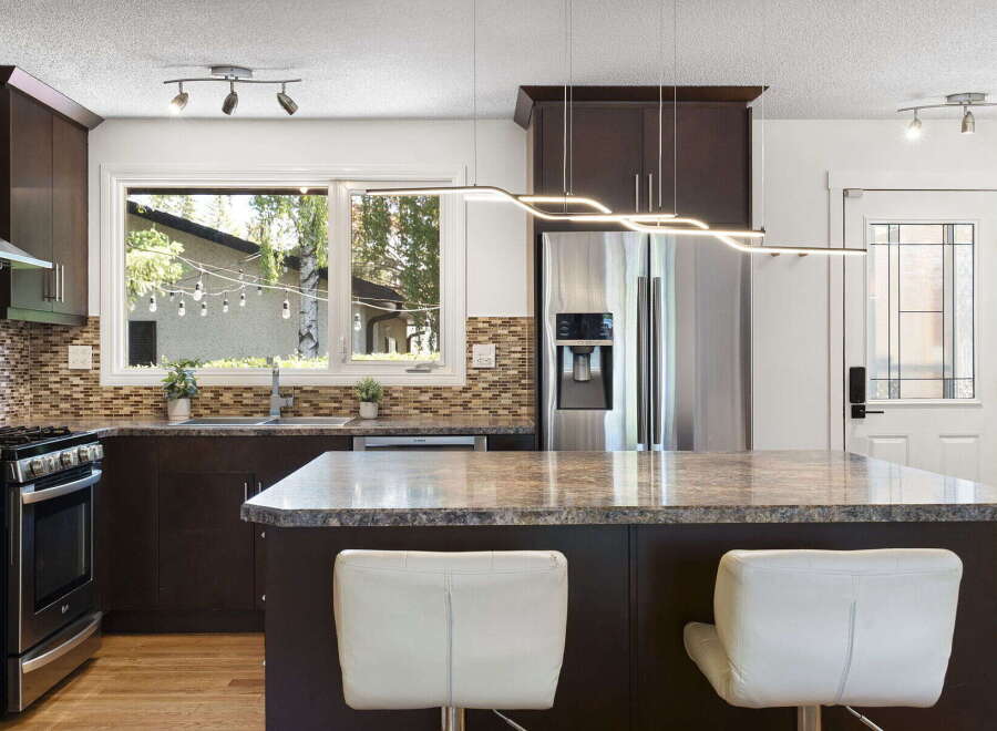 This modern kitchen boasts dark wood cabinetry and a sleek granite-topped island, perfect for casual dining or entertaining.
