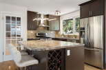Discover this stunning kitchen featuring dark wood cabinetry, a sleek stainless steel range hood, and a beautiful granite-look countertop island with a built-in wine rack.