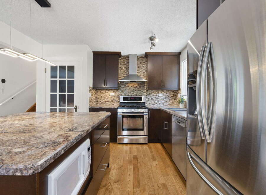 Experience modern living in this stunning kitchen, featuring sleek dark wood cabinetry and a beautiful granite-topped island with an integrated microwave.