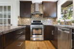 This modern kitchen boasts dark wood cabinetry and a sleek stainless steel range, complemented by a stylish mosaic tile backsplash.