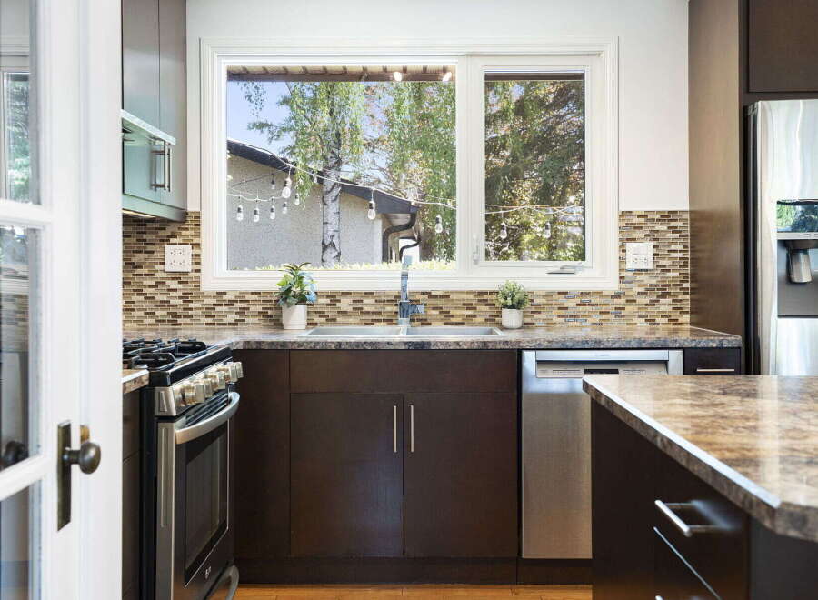 This kitchen boasts a sleek, modern design with dark cabinetry and a beautiful mosaic tile backsplash.