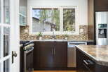 This kitchen boasts a sleek, modern design with dark cabinetry and a beautiful mosaic tile backsplash.