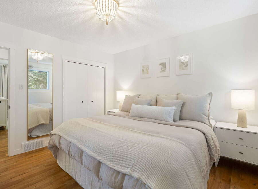 This serene bedroom features a plush king-sized bed adorned with soft, neutral-toned linens and decorative pillows.