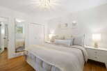 This serene bedroom features a plush king-sized bed adorned with soft, neutral-toned linens and decorative pillows.