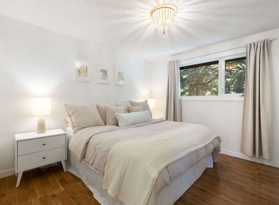 Experience serene comfort in this beautifully appointed bedroom, featuring a plush bed adorned with neutral-toned linens and accent pillows.