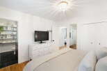 This charming bedroom features a modern white dresser with a flat-screen TV, complemented by a stylish beaded chandelier.